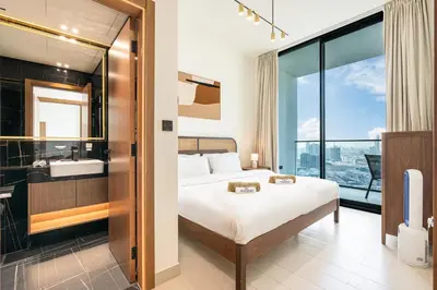 a bedroom with a bed and a bathroom with a window at Sleek Modern Home in the Heart of JVC in Dubai