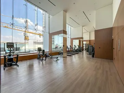 a gym with a bunch of exercise equipment in a room with windows at Sleek Modern Home in the Heart of JVC in Dubai