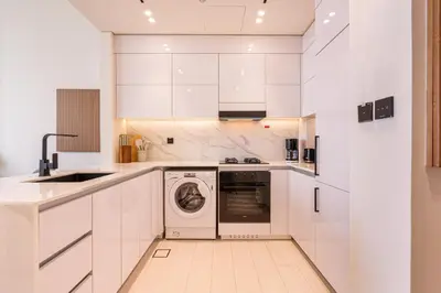 a kitchen with white cabinets and a washer and dryer at Sleek Modern Home in the Heart of JVC in Dubai