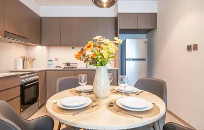 a kitchen with a table with chairs and a vase of flowers at Dream Apartment with Burj Khalifa & Fountain Views in Dubai