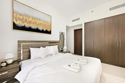 a bedroom with a large white bed with two towels on it at Bloomfields Tranquil 2BR in Dania 4 in Dubai