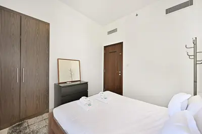 a white bedroom with a bed and a mirror at Bloomfields Tranquil 2BR in Dania 4 in Dubai