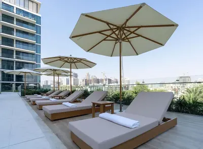 a row of lounge chairs and umbrellas on a roof at Contemporary Studio with Premium Design in JVC in Dubai