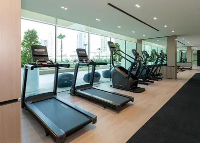 a gym with a row of treadms and elliptical machines at Contemporary Studio with Premium Design in JVC in Dubai