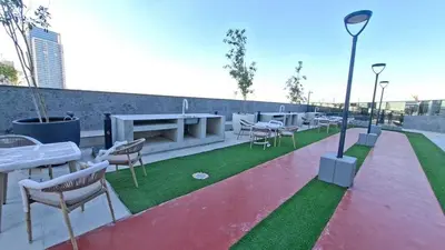 a rooftop patio with tables and chairs and grass at Cloud Tower 1br With Parking Pool Gym & Sports Facilities in Dubai