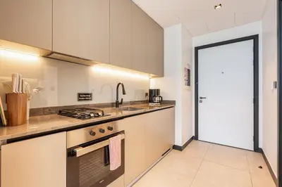 a kitchen with white cabinets and a stove top oven at Central Modern Studio with Floor to Ceiling Windows in Dubai