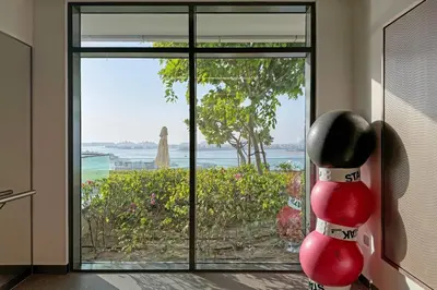 a room with a glass door with a view of the ocean at Miami Vibes - 1BR with Private Beach, Sea, Palm View in Dubai