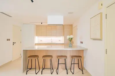 a kitchen with a island with four stools at Newly renovated, near the beach, with a Marina View in Dubai