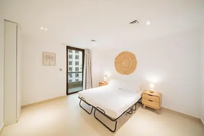 a white bedroom with a bed and a window at Newly renovated, near the beach, with a Marina View in Dubai