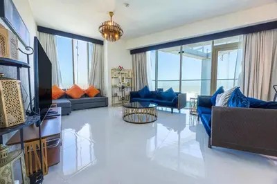 a living room with blue couches and a television at Miracle View in Dubai