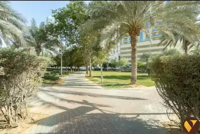 a street with palm trees in front of a building at Vogue JVC Jeewar Tower near Circle Mall, One Bedroom Apartment with Balcony and City View, Access to all Amenities in Dubai