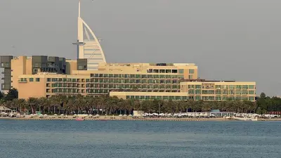 a large building with a beach in front of the water at Palm Jumeirah gem with direct beach access in Dubai