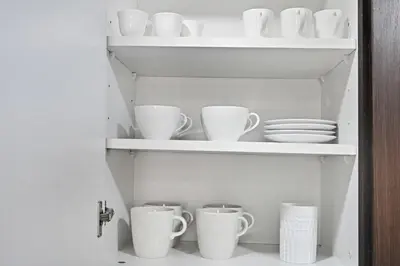 a cupboard filled with white cups and plates at Bloomfields Homey 1BR in Al Ramth 37 in Dubai