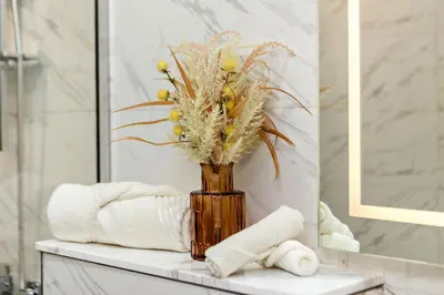 a vase with flowers on a table in a bathroom at Wonderful 1BR Apartment at East Crest in Dubai