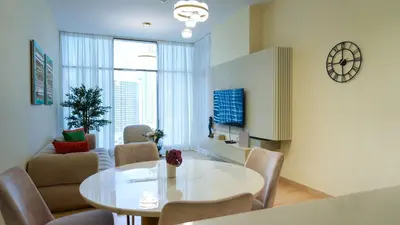 a living room with a table and chairs and a clock at Modern 3BR Full Canal & Burj Khalifa View 2 in Dubai