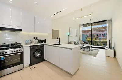 a white kitchen with a stove and a dishwasher at Stunning 1 br modern luxury residence at JVC in Dubai