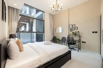 a bedroom with a large white bed with a chandelier at Stylish pool view 1BR in Barsha South sleeps 5 in Dubai