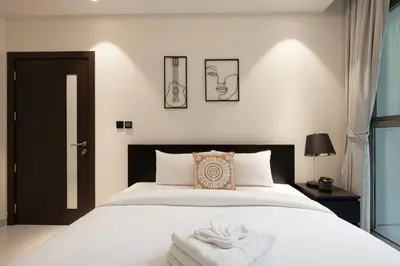 a bedroom with a white bed with a towel on it at Stylish pool view 1BR in Barsha South sleeps 5 in Dubai