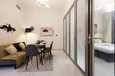 a living room with a couch and a table and a bed at Stylish pool view 1BR in Barsha South sleeps 5 in Dubai