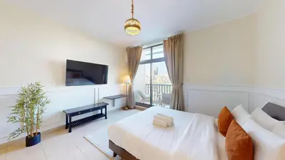 a white room with a bed and a tv at Vacationer l Spacious Studio l Canal View l The Greens in Dubai