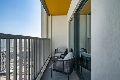 a balcony with two chairs and a table on a building at Modern 1BR with Guest Room l Sobha Hartland The Crest Tower C in Dubai