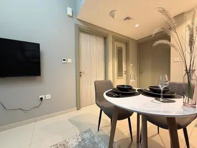 a dining room with a table with chairs and a television at Zada Tower 1 Bedroom Apartment in Business Bay in Dubai