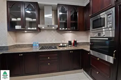 a kitchen with wooden cabinets and a stove top oven at Full View Burj Khalifa and Fountains -Souk Al Bahar- Dream View holiday Home Rent in Dubai
