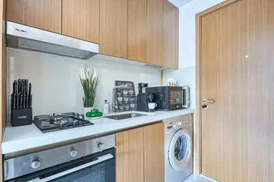a kitchen with a stove top oven next to a washing machine at Frank Porter - Azizi Mirage 1 in Dubai