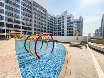 a pool with a water slide in front of a building at Frank Porter - Azizi Mirage 1 in Dubai
