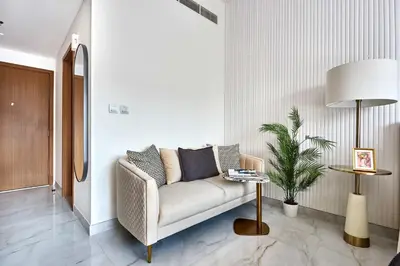 a living room with a couch and a potted plant at Frank Porter - Azizi Mirage 1 in Dubai