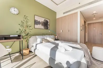 a bedroom with two beds and a clock on the wall at Sleek Modern Studio with Direct view of Dubai Skyline - Farhad Azizi Residence, Al Jaddaf by Deluxe Holiday Homes in Dubai
