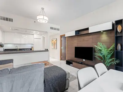 a kitchen and living room with a couch and a tv at Cozy and Elegant 1 BDR In Noura Tower-37 in Dubai