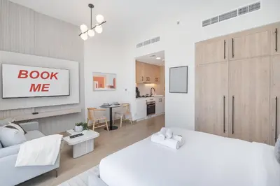 a white bedroom with a bed and a living room at StayShort - Spacious Studio in Town Square Sleeps 2 in Nadd Shubayḩ
