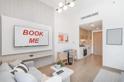 a living room with a white couch and a table at StayShort - Spacious Studio in Town Square Sleeps 2 in Nadd Shubayḩ