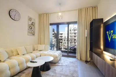 a living room with a couch and a tv at Silk Valley - Green View Oasis: Stylish 2BR in Dubai’s Town Square in Dubai