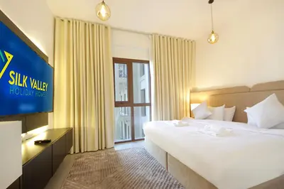 a hotel room with a large bed and a television at Silk Valley - Green View Oasis: Stylish 2BR in Dubai’s Town Square in Dubai