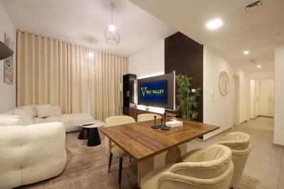 a living room with a couch and a table with a television at Silk Valley - Green View Oasis: Stylish 2BR in Dubai’s Town Square in Dubai