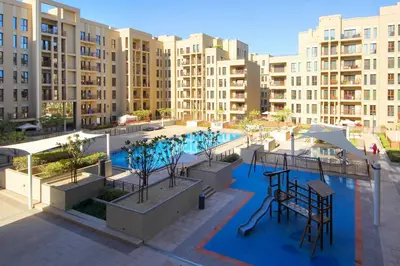 an apartment complex with a swimming pool and buildings at Silk Valley - Green View Oasis: Stylish 2BR in Dubai’s Town Square in Dubai