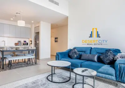 a living room with a blue couch and a kitchen at Premium 2BR Downtown Dubai Near Burj & Dubai Mall Hosted by Desert City Stays in Dubai