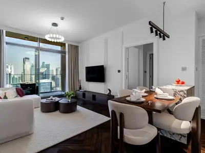 a living room with a table and chairs and a television at Stunning High-Floor 1BR Burj Khalifa & Canal Views in Dubai