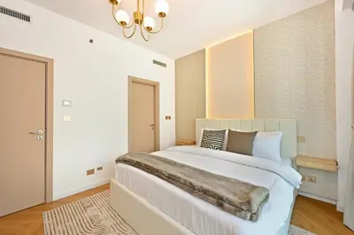 a bedroom with a large white bed and a chandelier at Curated High-Floor 2BR Sofa Bed Marina Water View in Dubai
