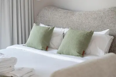 a white bed with four pillows on it at Chic Studio in Sports City Pool, Gym, Sauna in Dubai