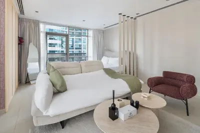 a bedroom with a bed and a chair and a table at Chic Studio in Sports City Pool, Gym, Sauna in Dubai