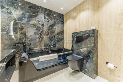 a bathroom with a toilet and a marble wall at Walking Distance To JBR Beach, The Walk, And Marina Mall, With Easy Access To The Metro And The Vibrant Marina Nightlife - DEC Towers 2, Dubai Marina by Deluxe Holiday Homes in Dubai