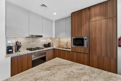 a kitchen with wooden cabinets and a counter top at New Downtown Bldg Near Burj View with Infinity Pool and SkyGym in Dubai