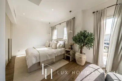 a white bedroom with a bed and a potted plant at LUX The Serene Springs Villa 3 in Dubai