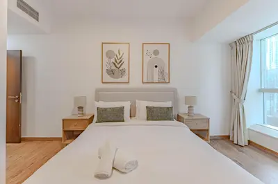 a bedroom with a white bed with two slippers on it at HAVN - 2 bedroom in Elite Residences, Dubai Marina in Dubai