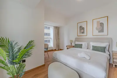 a bedroom with a white bed and a plant at HAVN - 2 bedroom in Elite Residences, Dubai Marina in Dubai