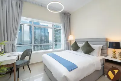 a bedroom with a bed and a desk and a window at Vogue JLT Lake City Tower near Marina and JBR, Studio Apartment with Lake and City Skyline View, Access to all Amenities in Dubai