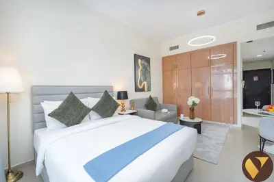 a bedroom with a large bed and a living room at Vogue JLT Lake City Tower near Marina and JBR, Studio Apartment with Lake and City Skyline View, Access to all Amenities in Dubai